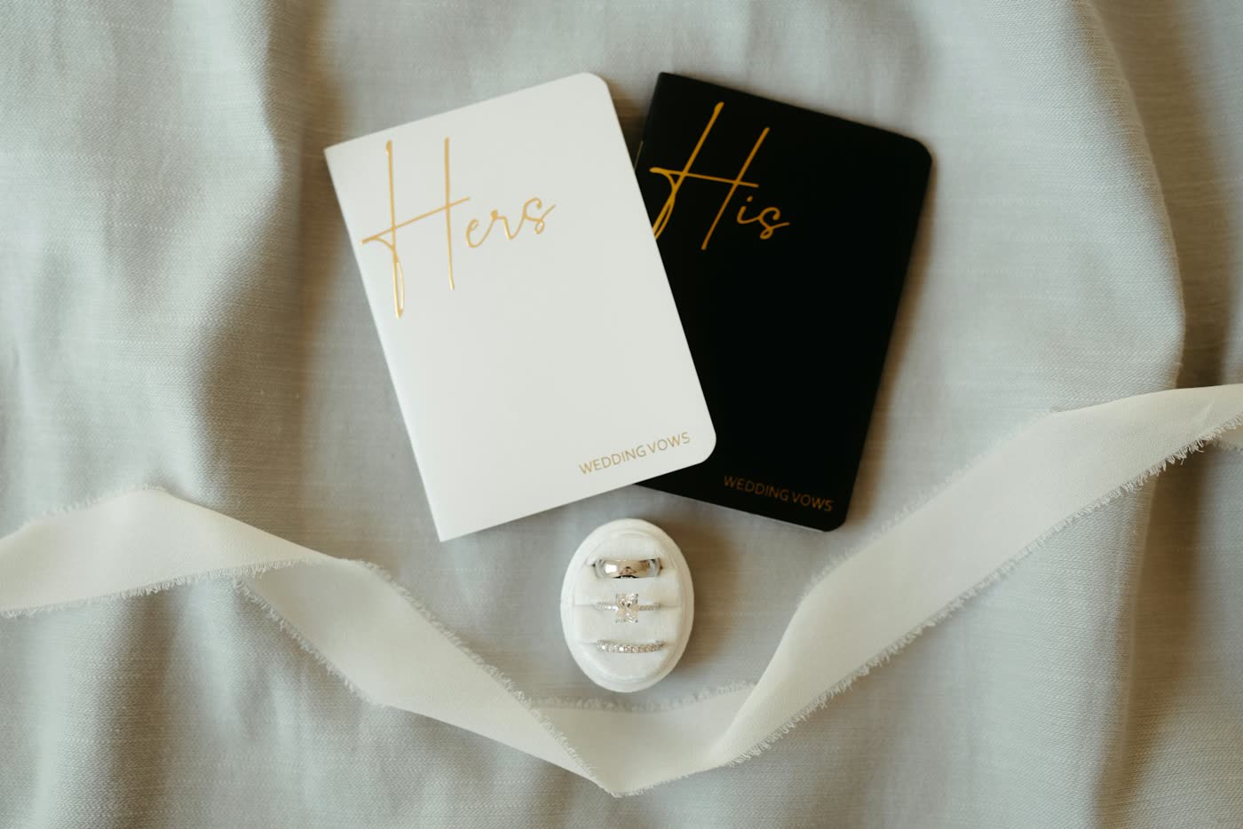 His and hers wedding vow notebooks laid beside the wedding rings