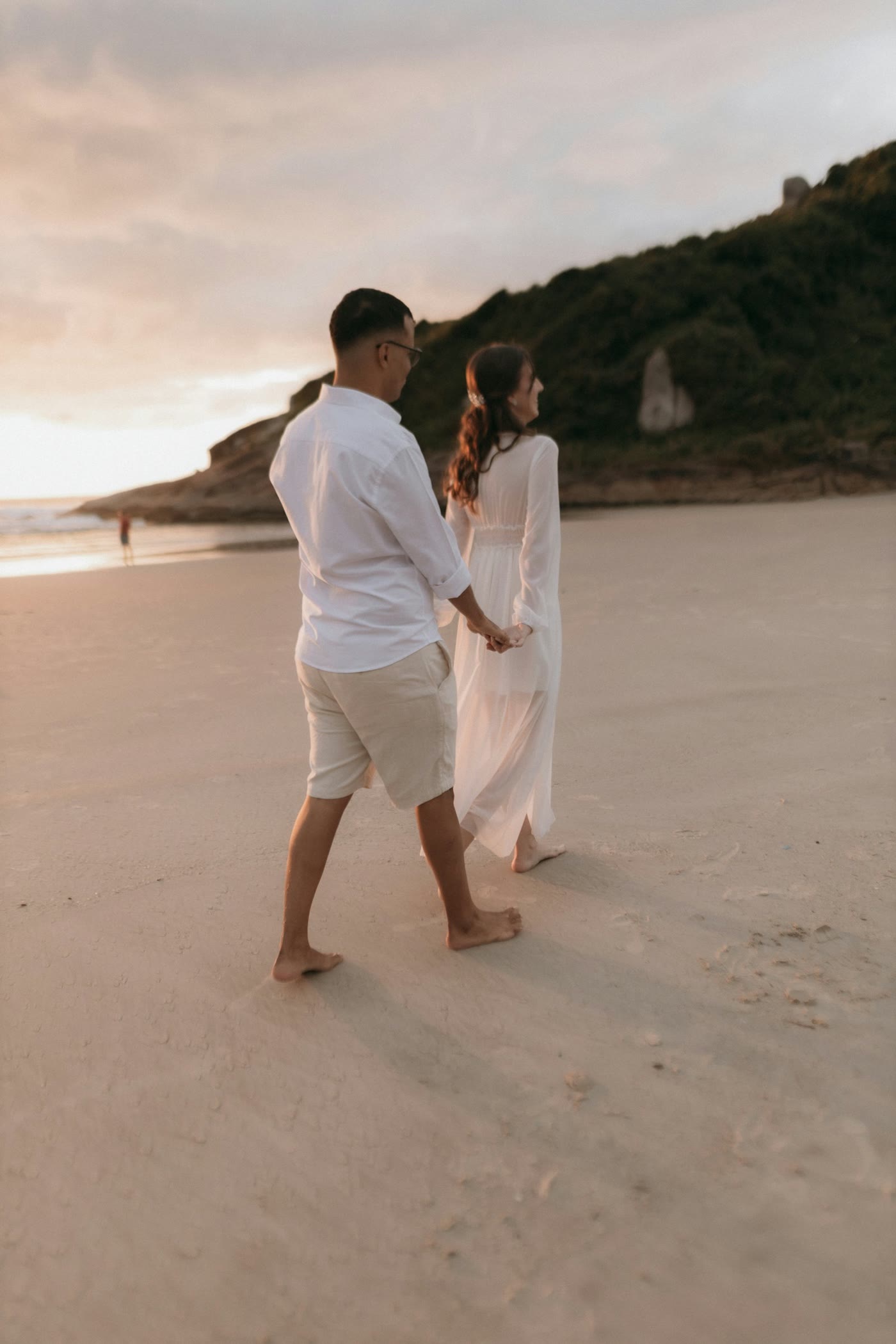 A couple walking hand in hand along the beach at golden hour