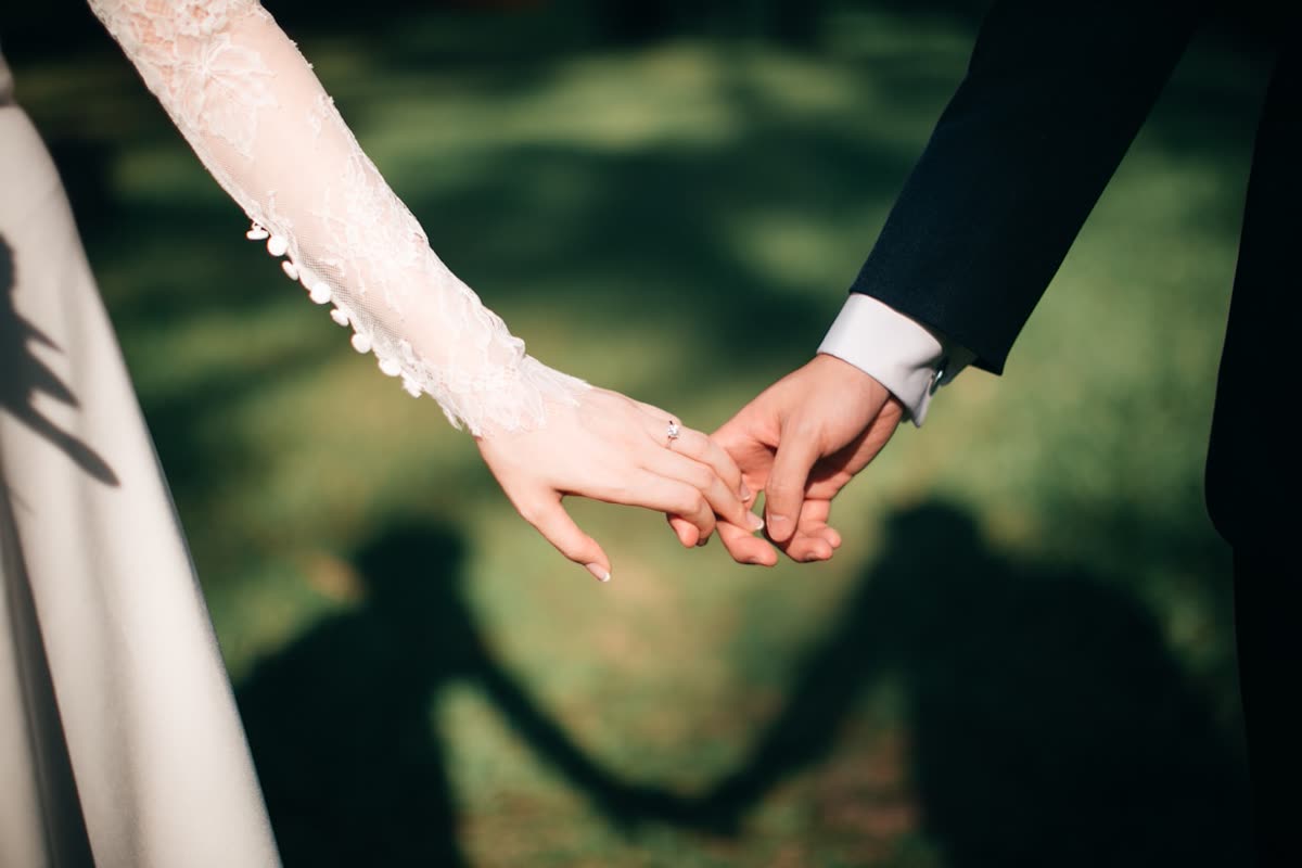 Close-up of a couple holding hands, wedding ring visible
